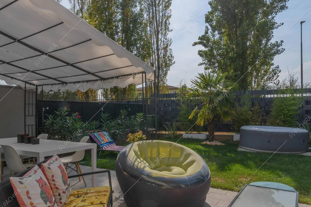 Giardino con idromassaggio, divano, pouf e tavolo bianco