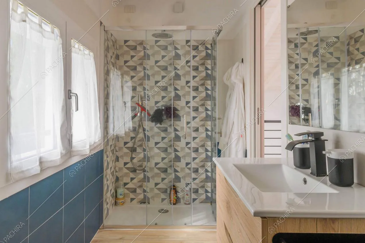 Bagno con parete in piastrelle blu, box doccia e pavimento in parquet