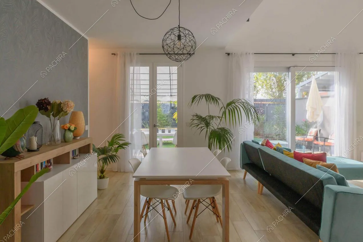 Tavolo da pranzo bianco nell'open space della villa con pavimento in parquet e divano in velluto