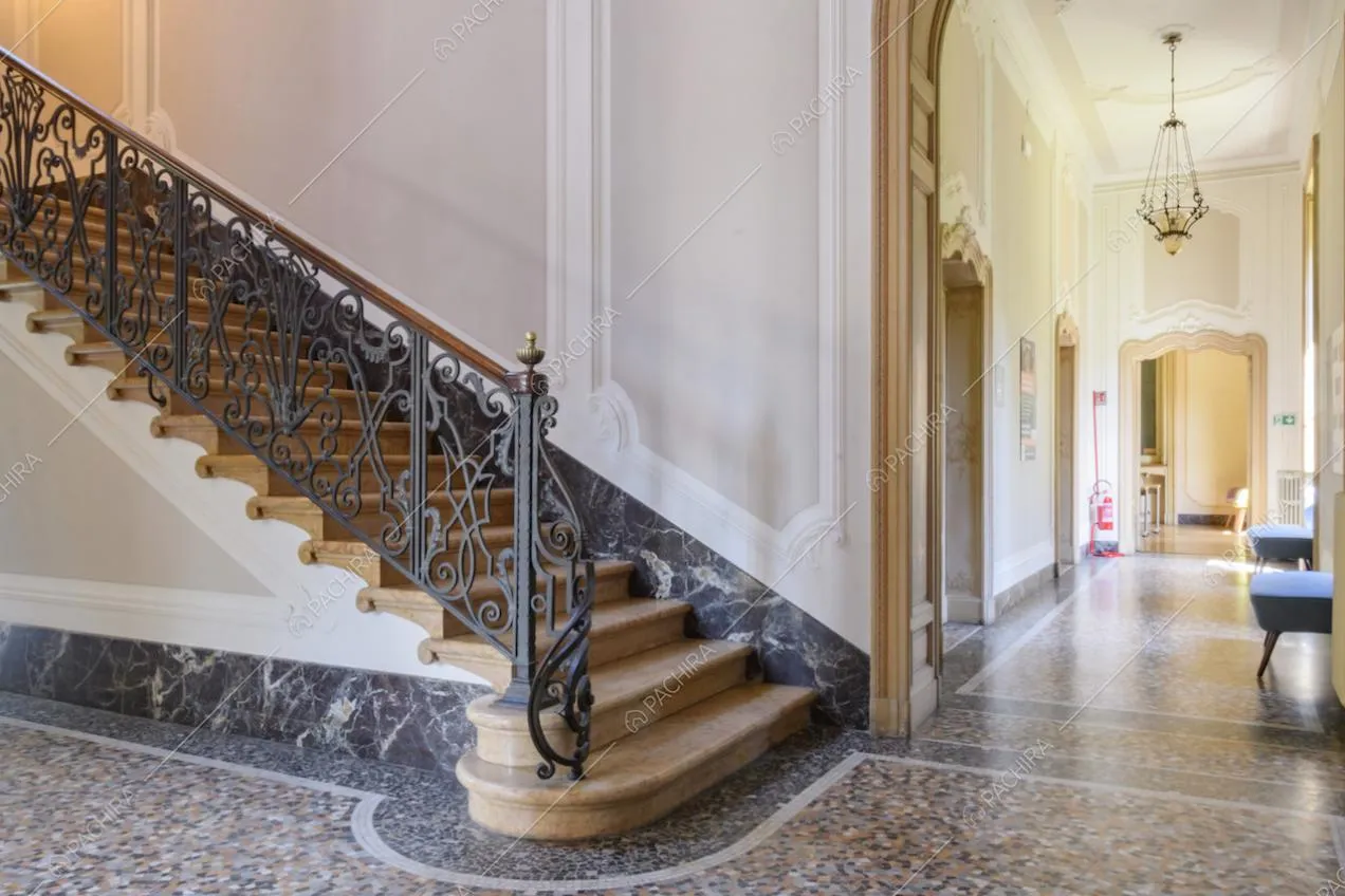 Scalone e vista sul corridoio dall'alto soffitto con boiserie