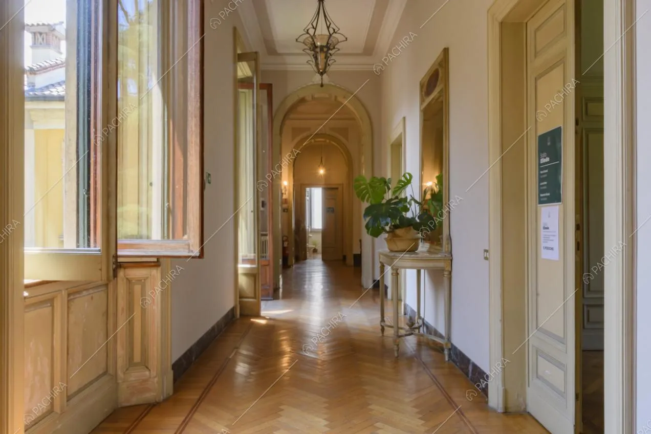Lungo corridoio con pavimento in parquet e soffitto con boiserie