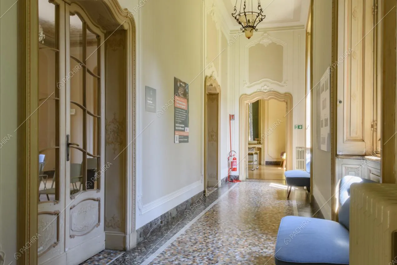 Luminoso corridoio con pavimento in graniglia, boiserie alle pareti e vista su un salone