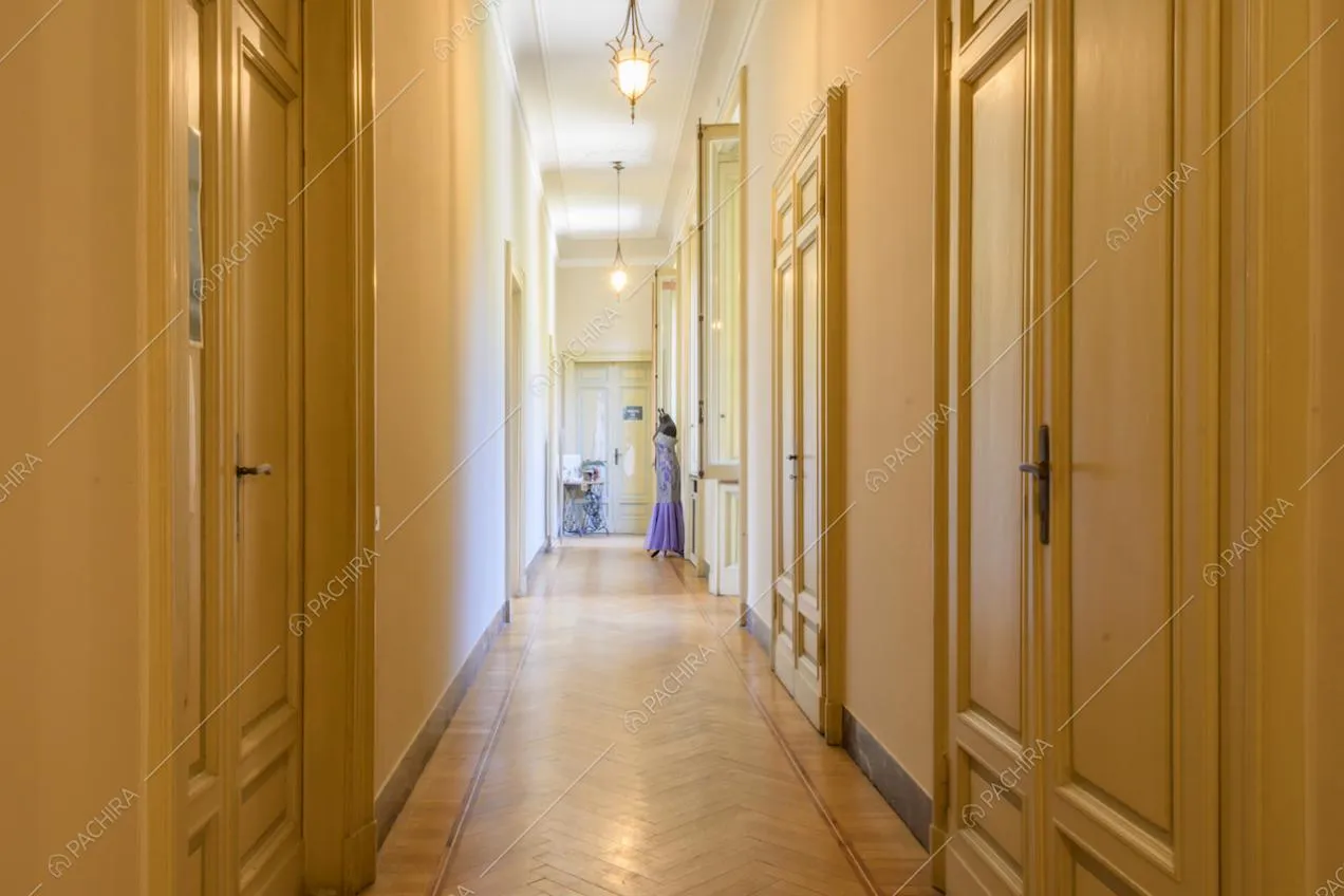 Porte con boiserie nel lungo corridoio con pavimento in parquet a spina di pesce