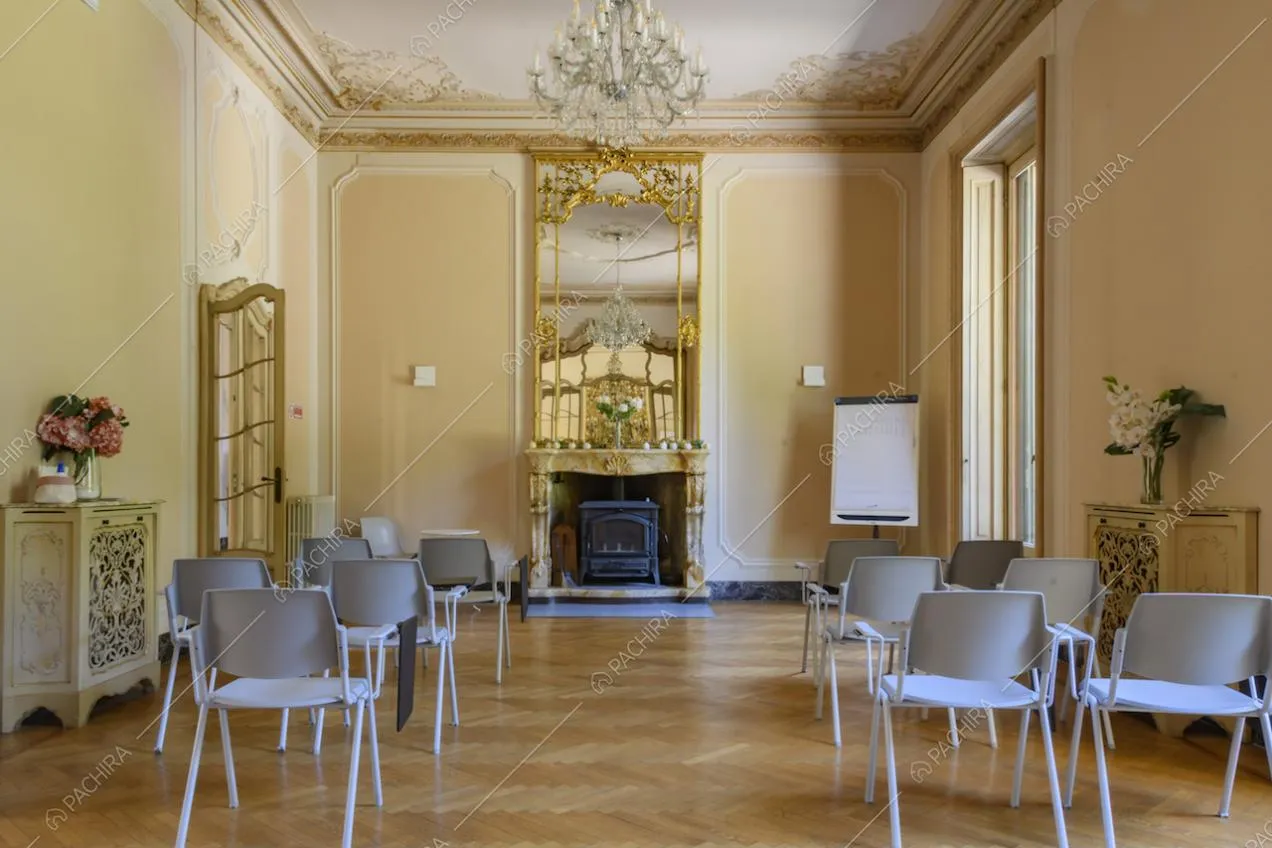 Luminoso salone con boiserie su soffitto e pareti, camino e maestoso specchio incastonato in una cornice dorata