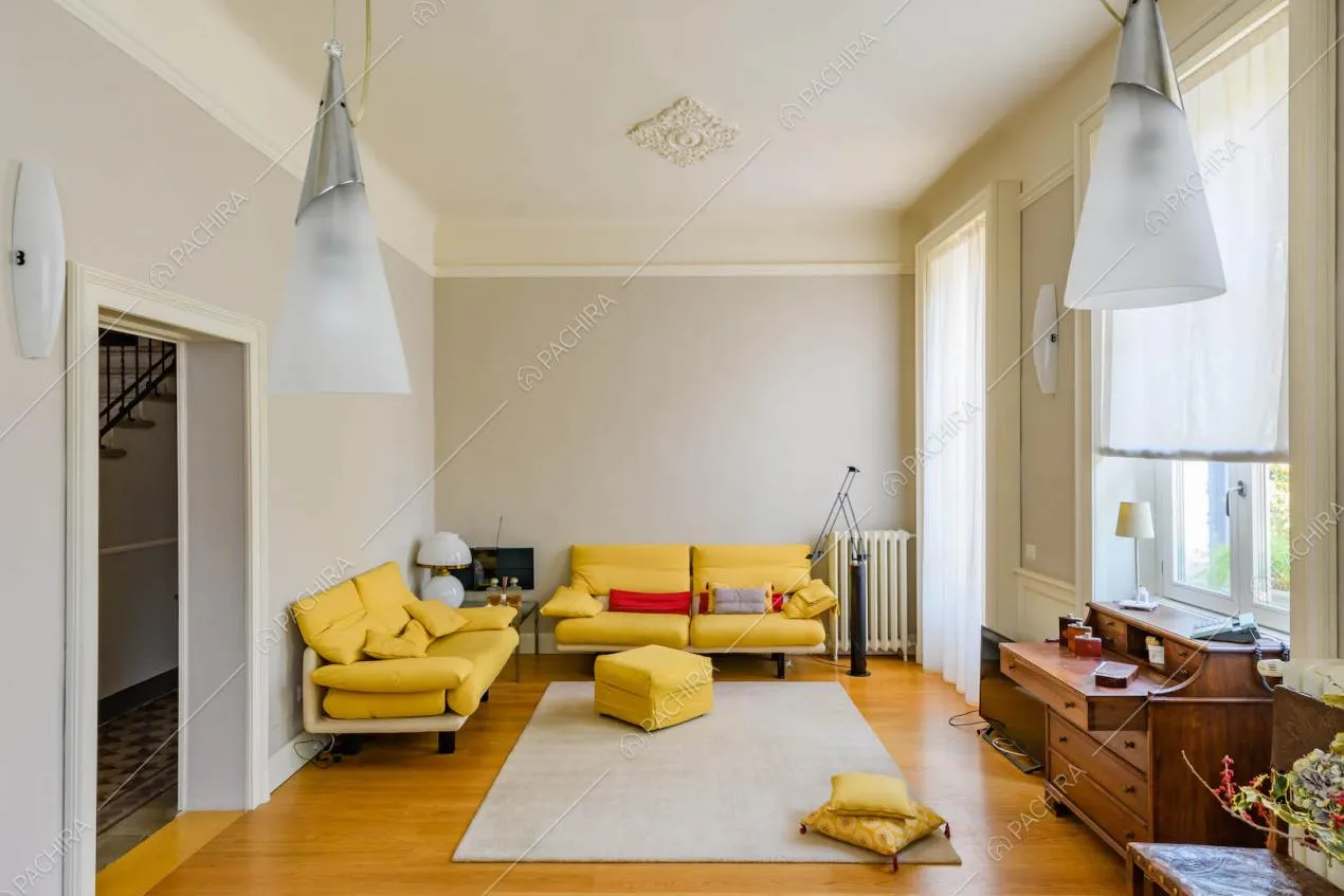 Luminoso salotto con divani gialli, pavimento in parquet e pareti grigie con boiserie