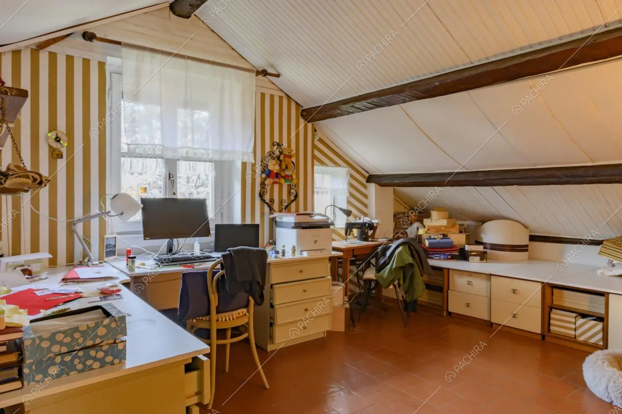 Nel solaio soffitto bianco con travi a vista, scrivania e pavimento in cotto