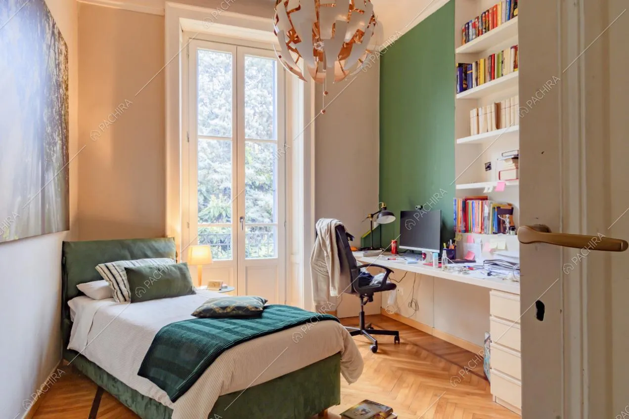 Camera da letto con pavimento in parquet a spina di pesce, parete verde e scrivania