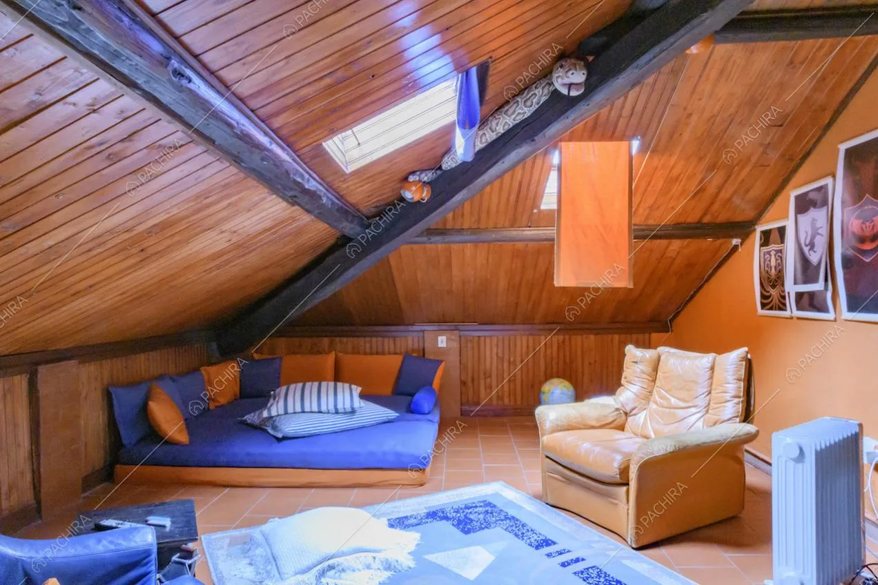 Soffitto in legno con travi a vista e lucernario nel solaio con divano e poltrone