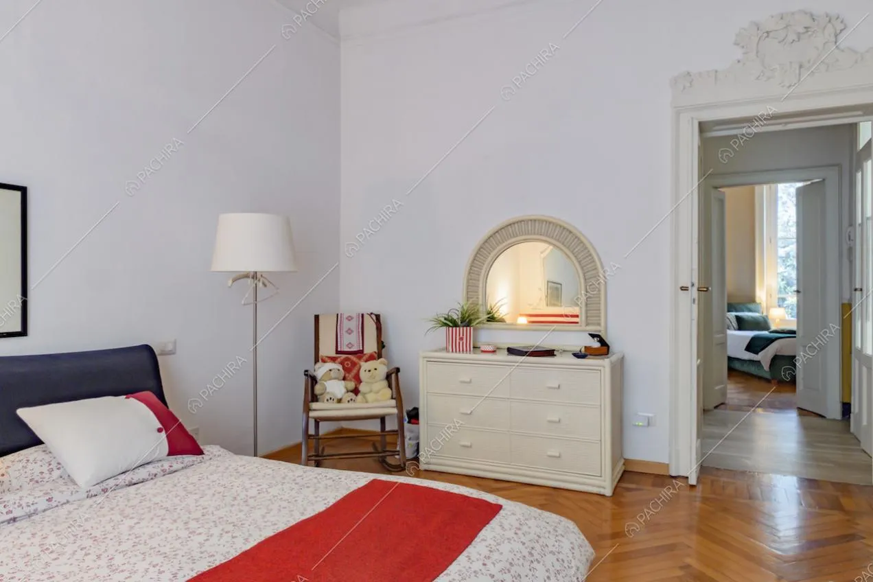 Camera da letto matrimoniale con pavimento in parquet a spina di pesce e boiserie