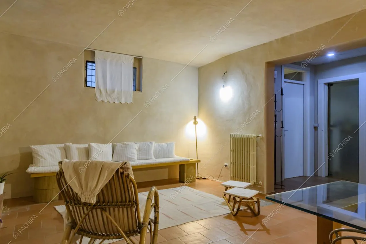 Vista sulla porta d'ingresso dalla sala con tavolo da pranzo, divano e pavimento in cotto