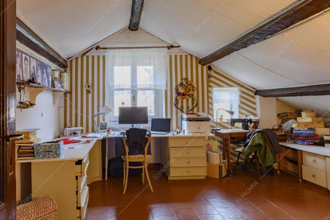 Solaio con travi in legno a vista sul soffitto, scrivania e carta da parati a righe