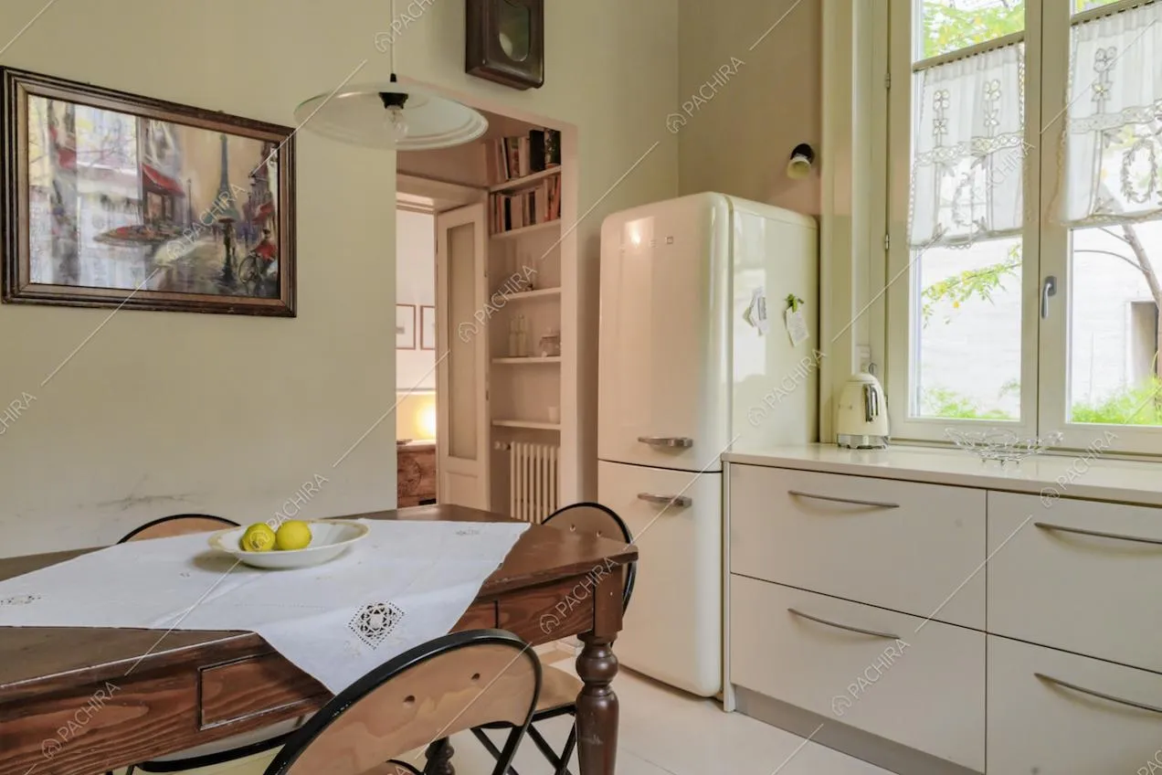 Luminosa cucina bianca a parete con tavolo da pranzo in legno