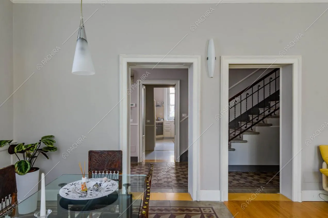 Dal tavolo da pranzo nella sala con pareti grigie vista sulle scale e sulla cucina a parete