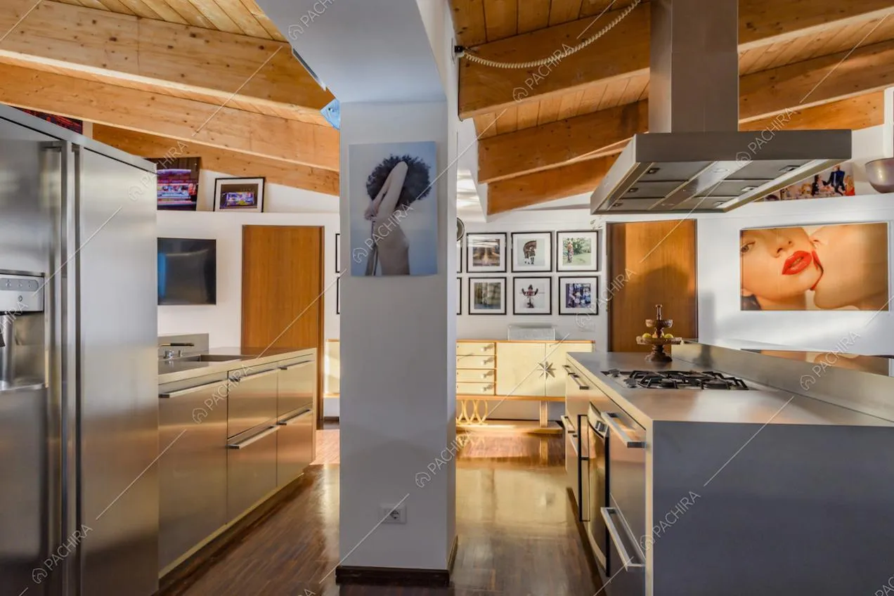 Cucina a vista con mobili metallizzati e pareti con quadri
