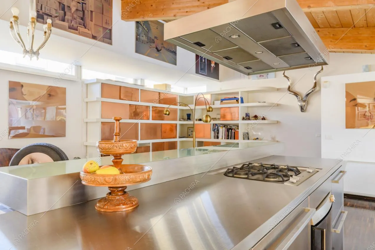 Dettaglio del piano di lavoro della cucina e libreria sullo sfondo