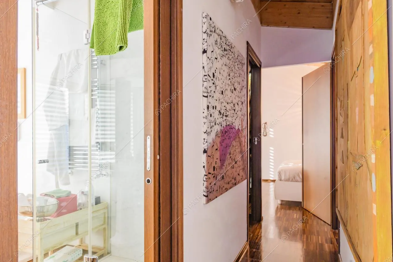Corridoio con quadri moderni appesi alle pareti e scorcio sul bagno