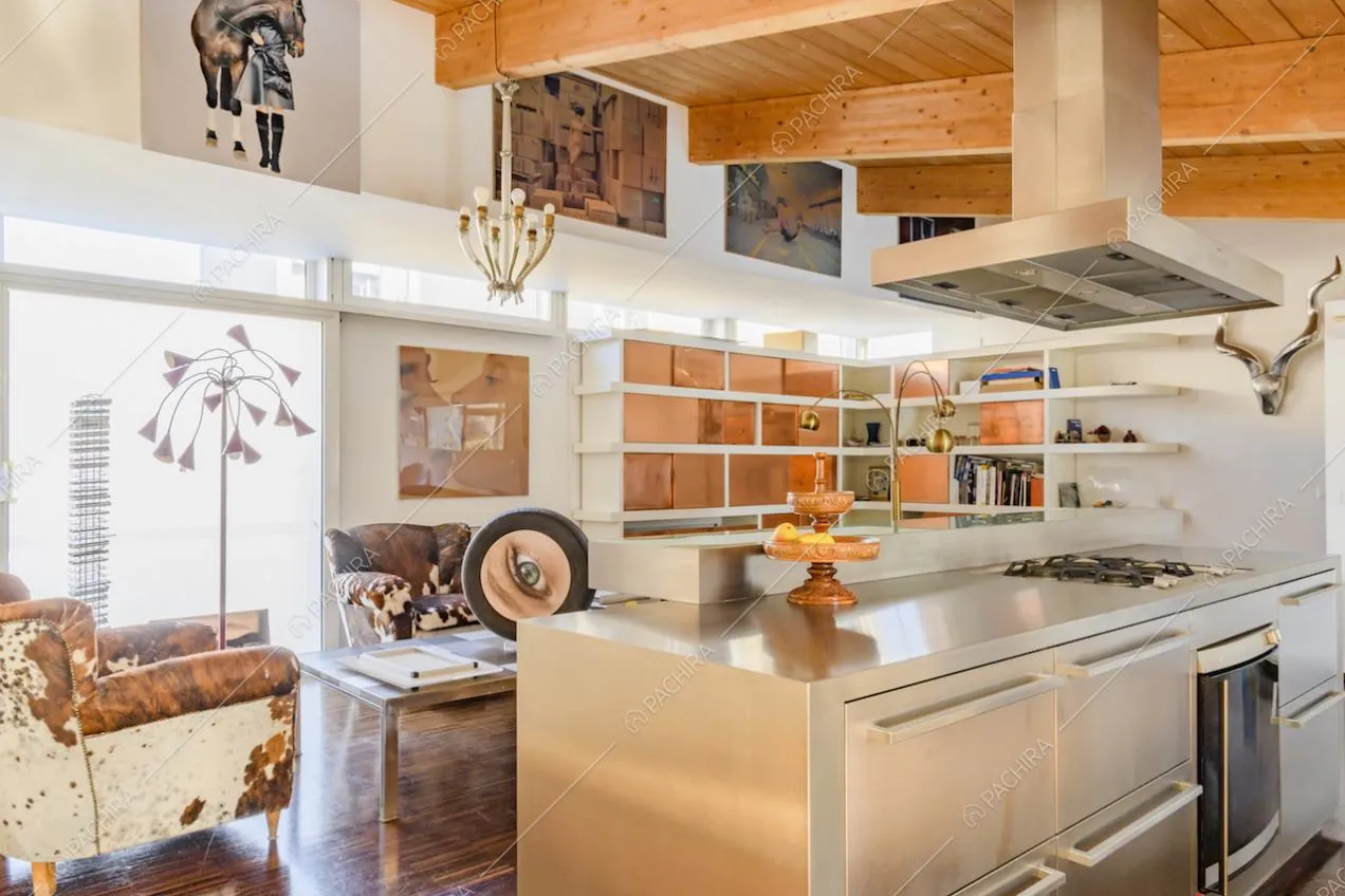 Angolo salotto con poltrone, libreria e cucina a isola