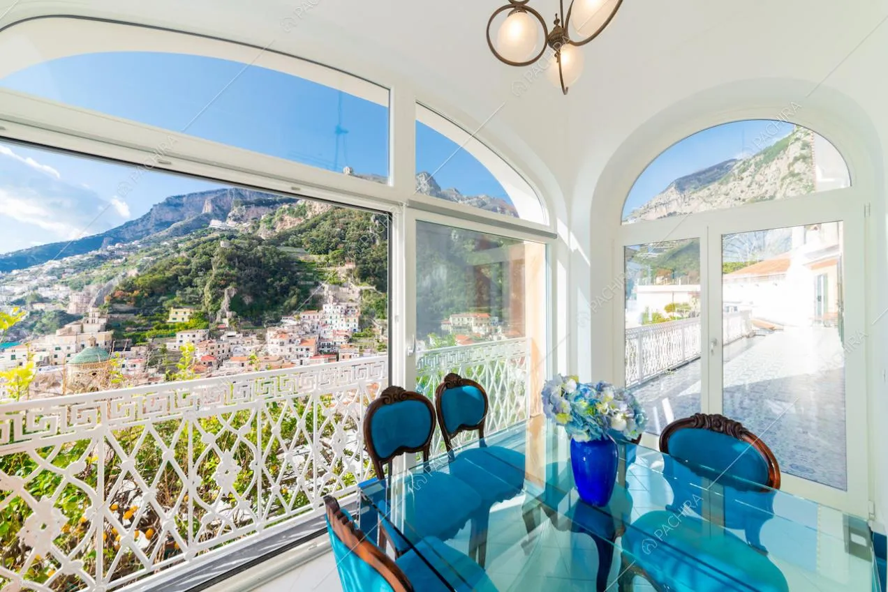 Zona pranzo circondata da vetrate e ringhiera bianca decorata
