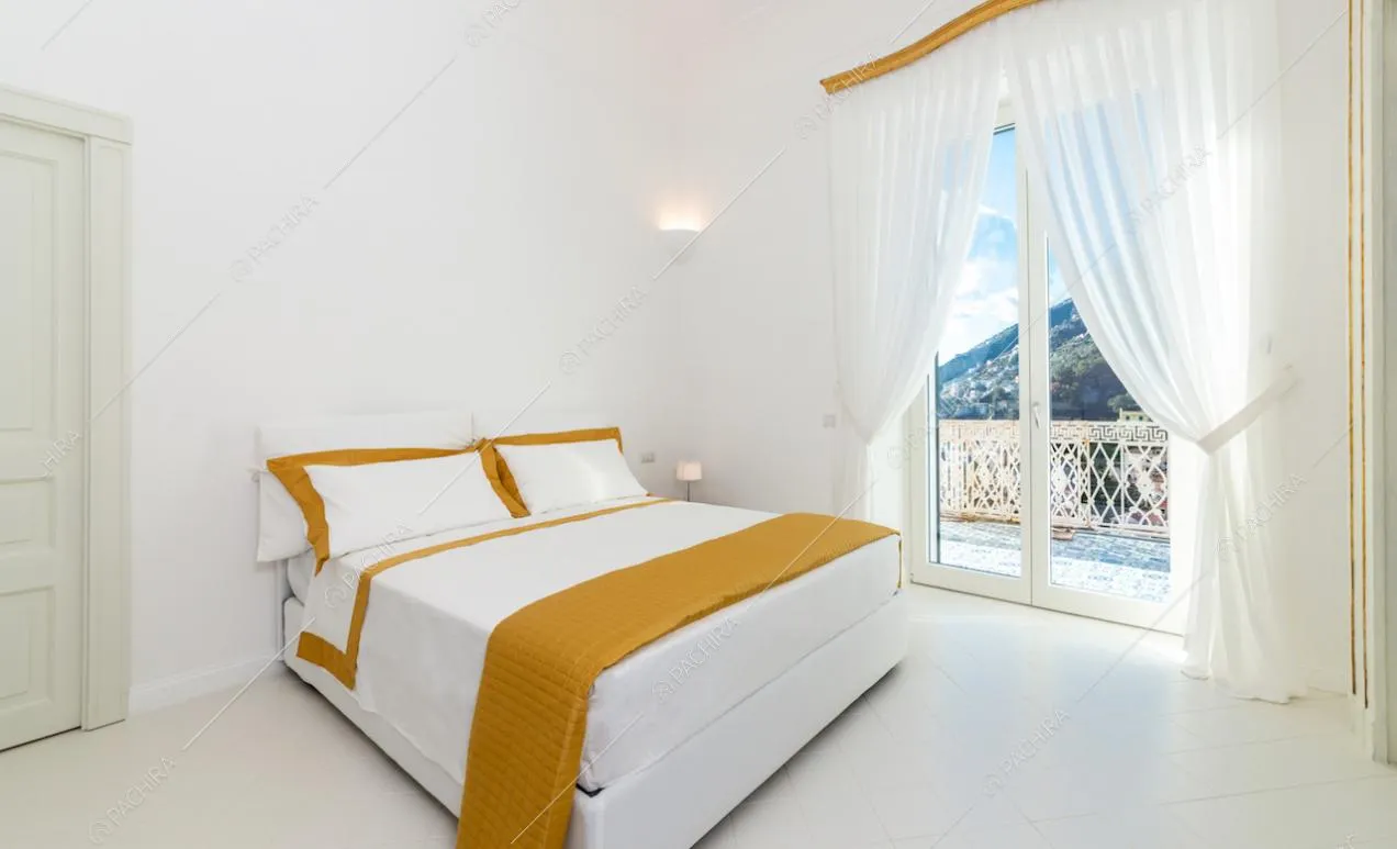 Letto matrimoniale vicino alla finestra con affaccio sulla costiera