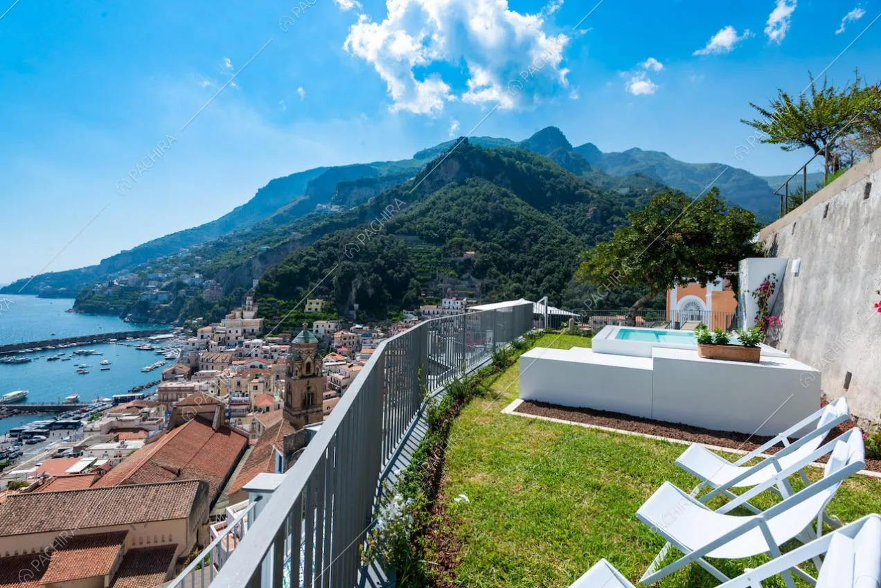 Giardino con piscina, sedie a sdraio e vista sulla costiera