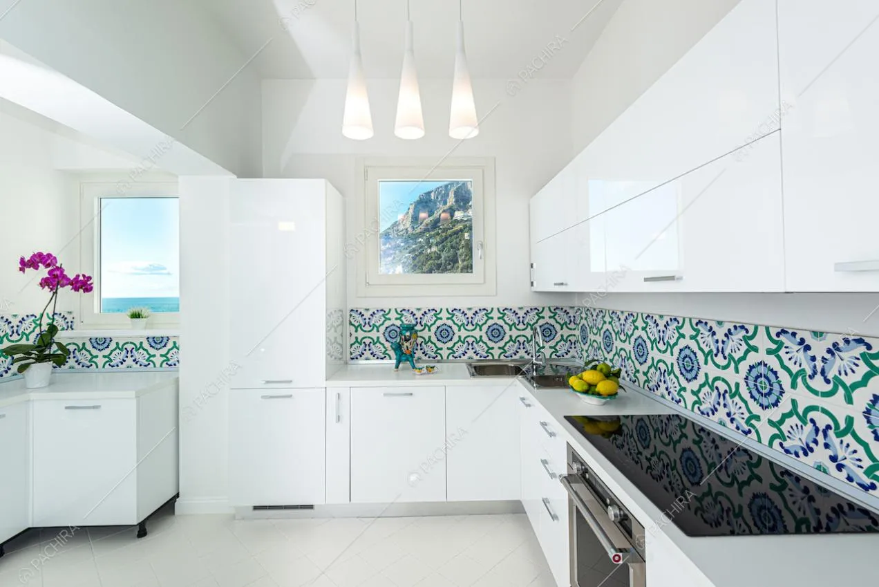 Mobili bianchi e fornelli a induzione nella cucina della villa