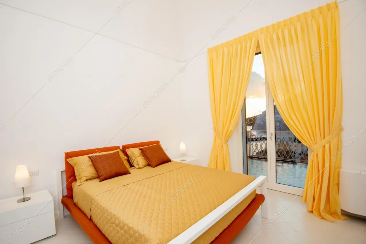 Letto matrimoniale e finestra con tenda gialla e vista sul mare
