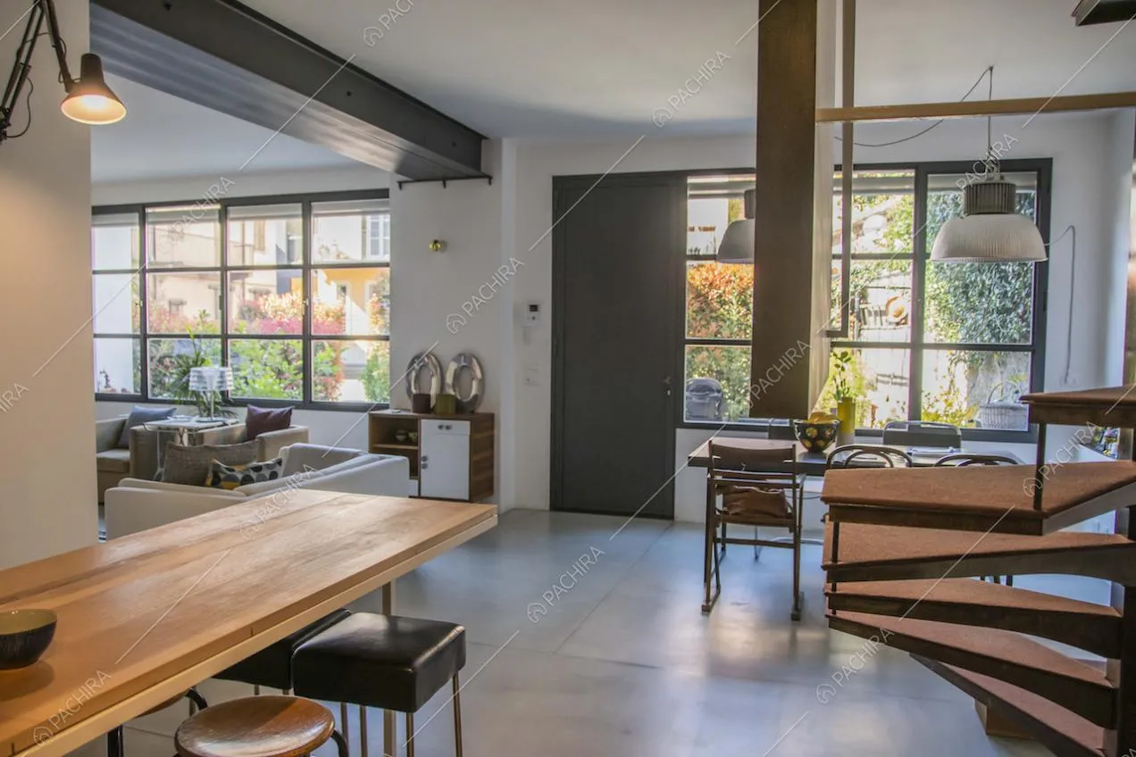 Isola in legno della cucina a vista, divani, finestre industriali e scala a chiocciola in metallo délabré