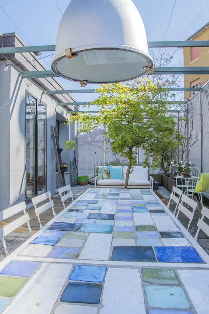 Tavolo con piastrelle e lampadario nella terrazza con divano da esterni