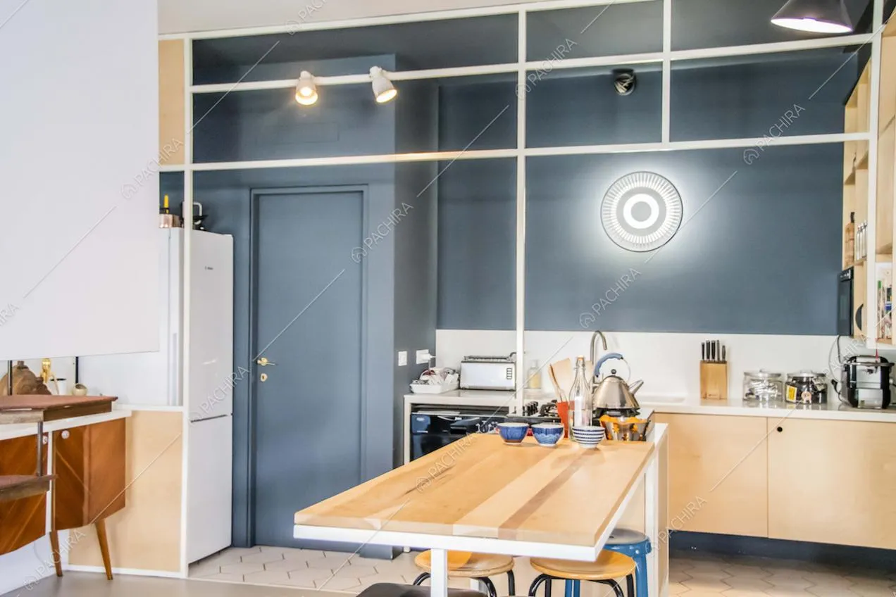 Cucina con parete blu, isola in legno e pavimento in cemento lisciato e cementine bianche