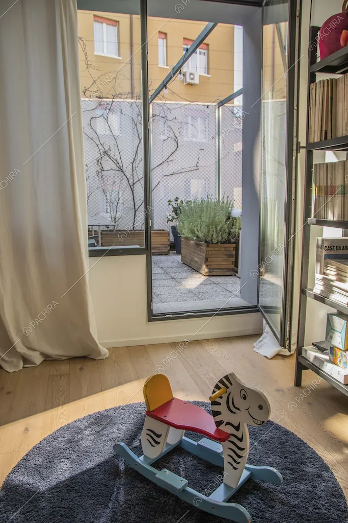 Camera con pavimento in parquet, libreria e porta-finestra per accedere alla terrazza