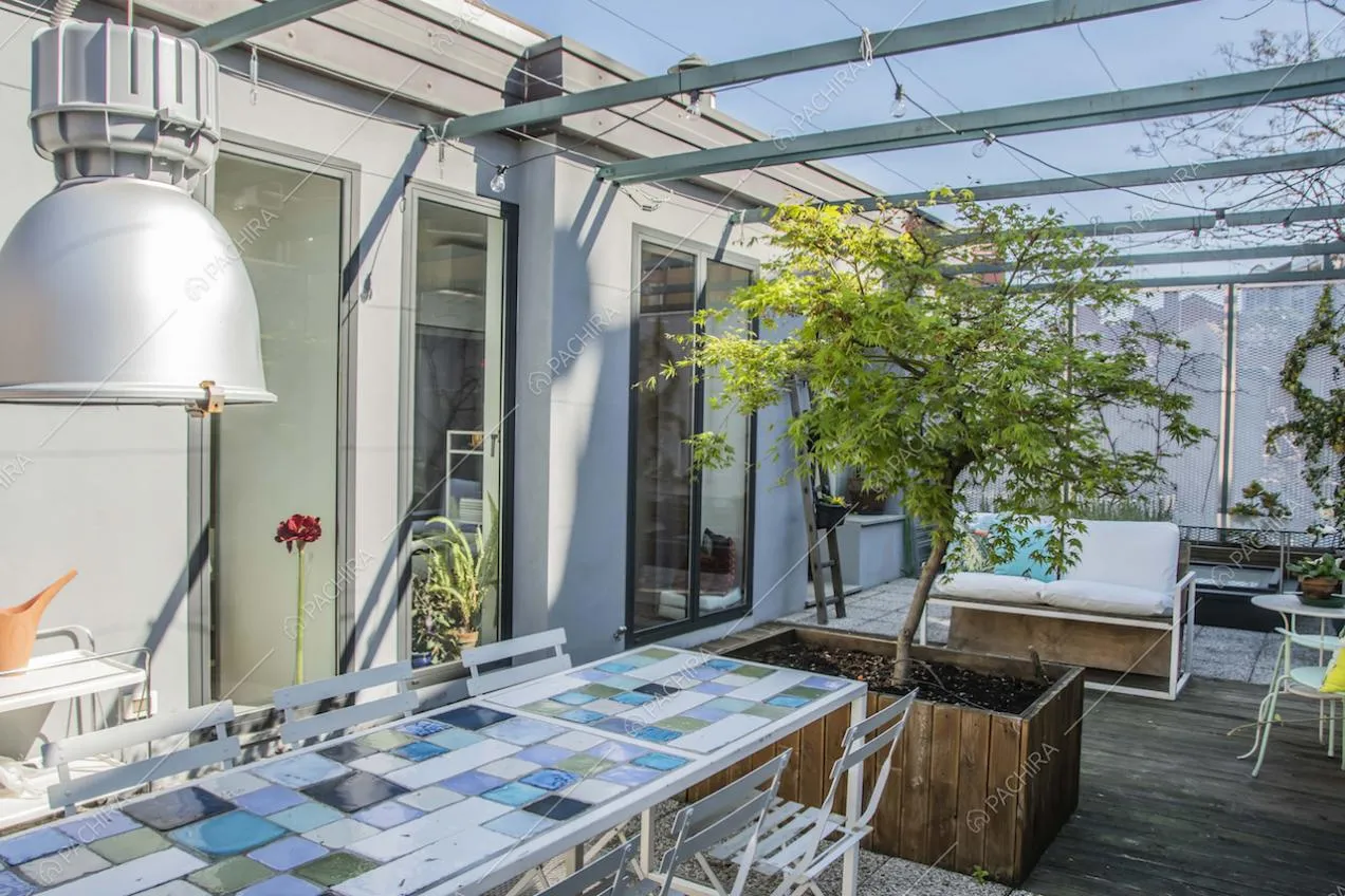Tavolo con piano in piastrelle nell'ampia terrazza con pavimento in parquet per esterni
