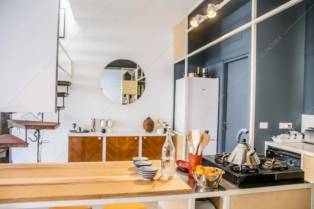 Cucina con fornelli a gas, parete blu e vista sulle scale autoportanti