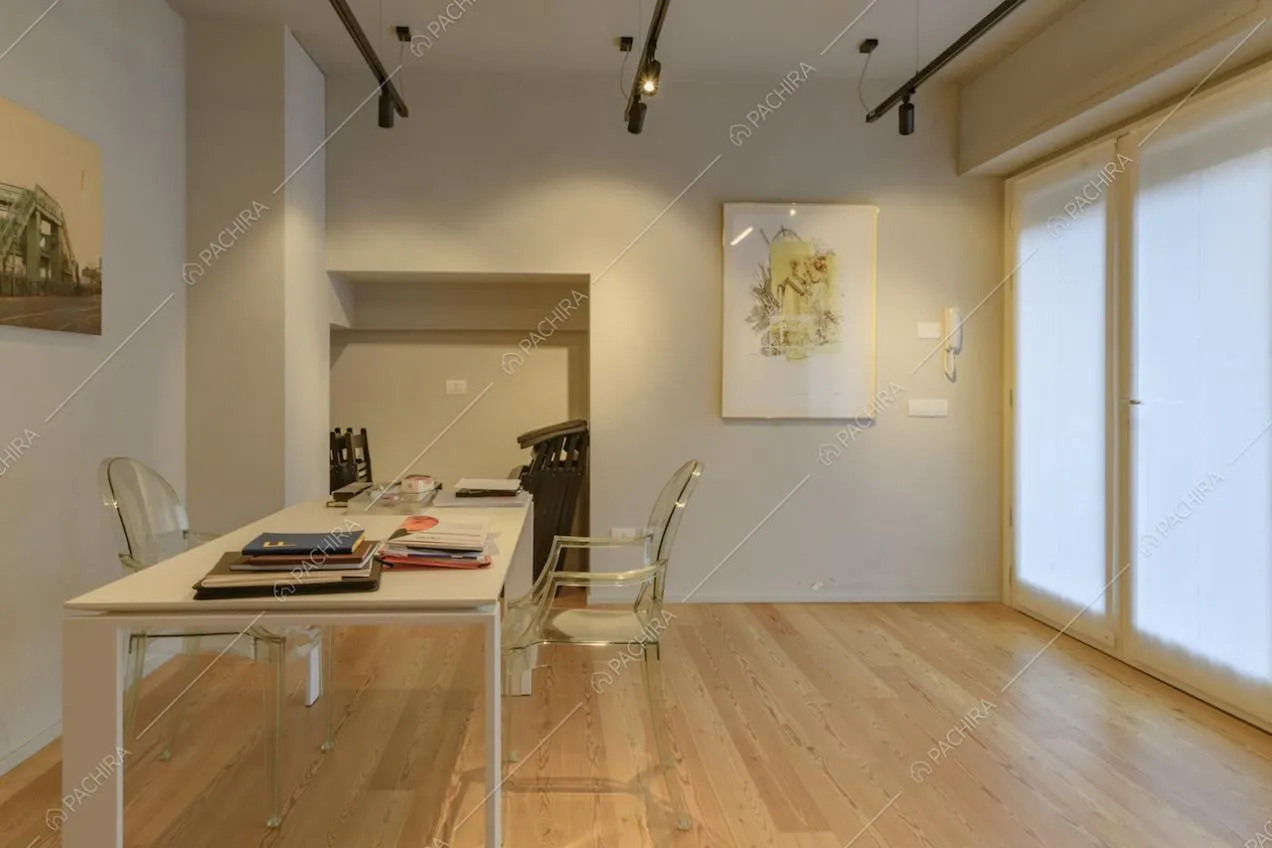 Studio con porta-finestra, scrivania bianca e pavimento in parquet