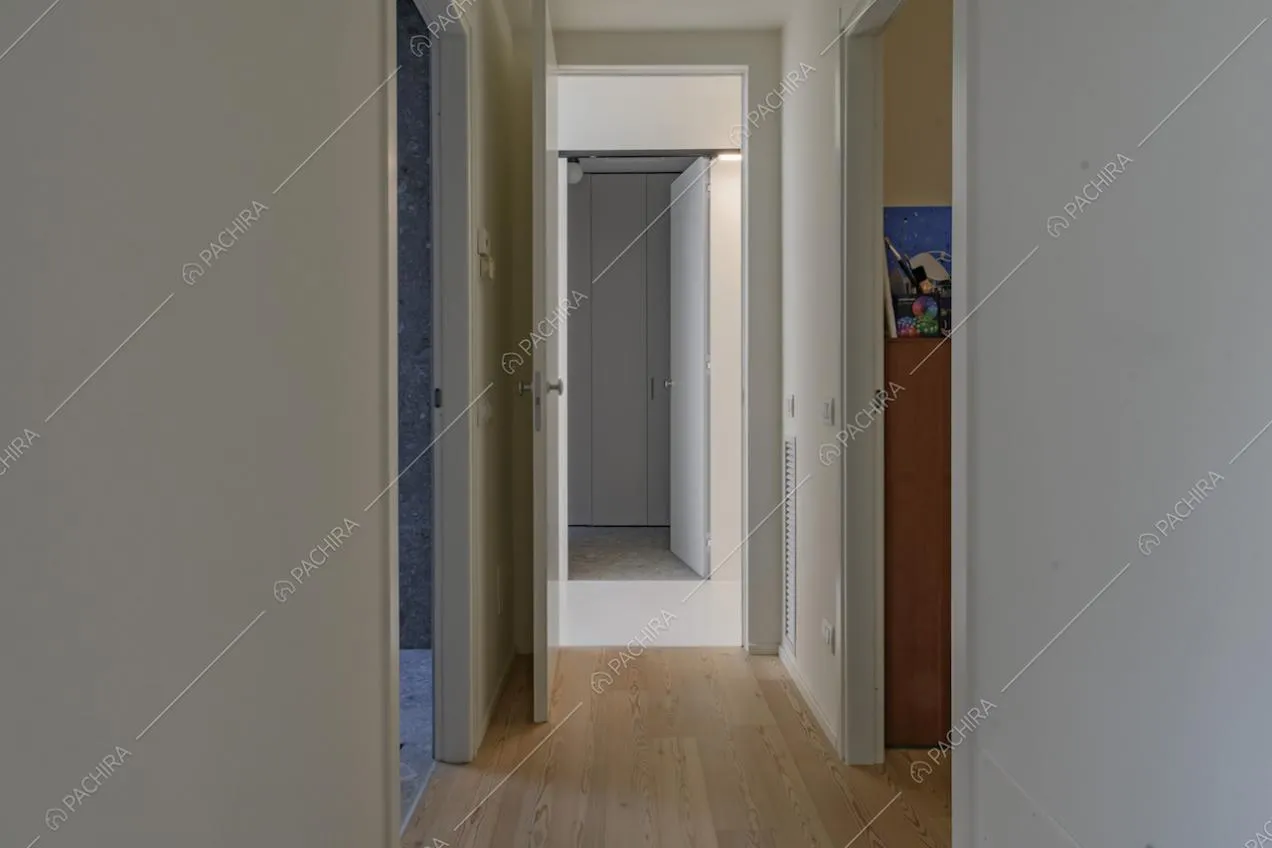 Corridoio con pavimento in parquet e scorcio su bagno e camera da letto