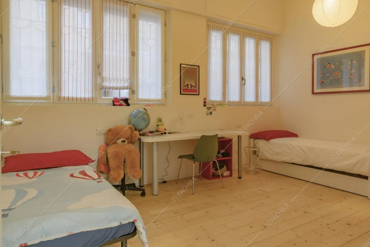 Camera da letto da bambini con due letti singoli, pavimento in parquet e pareti bianche