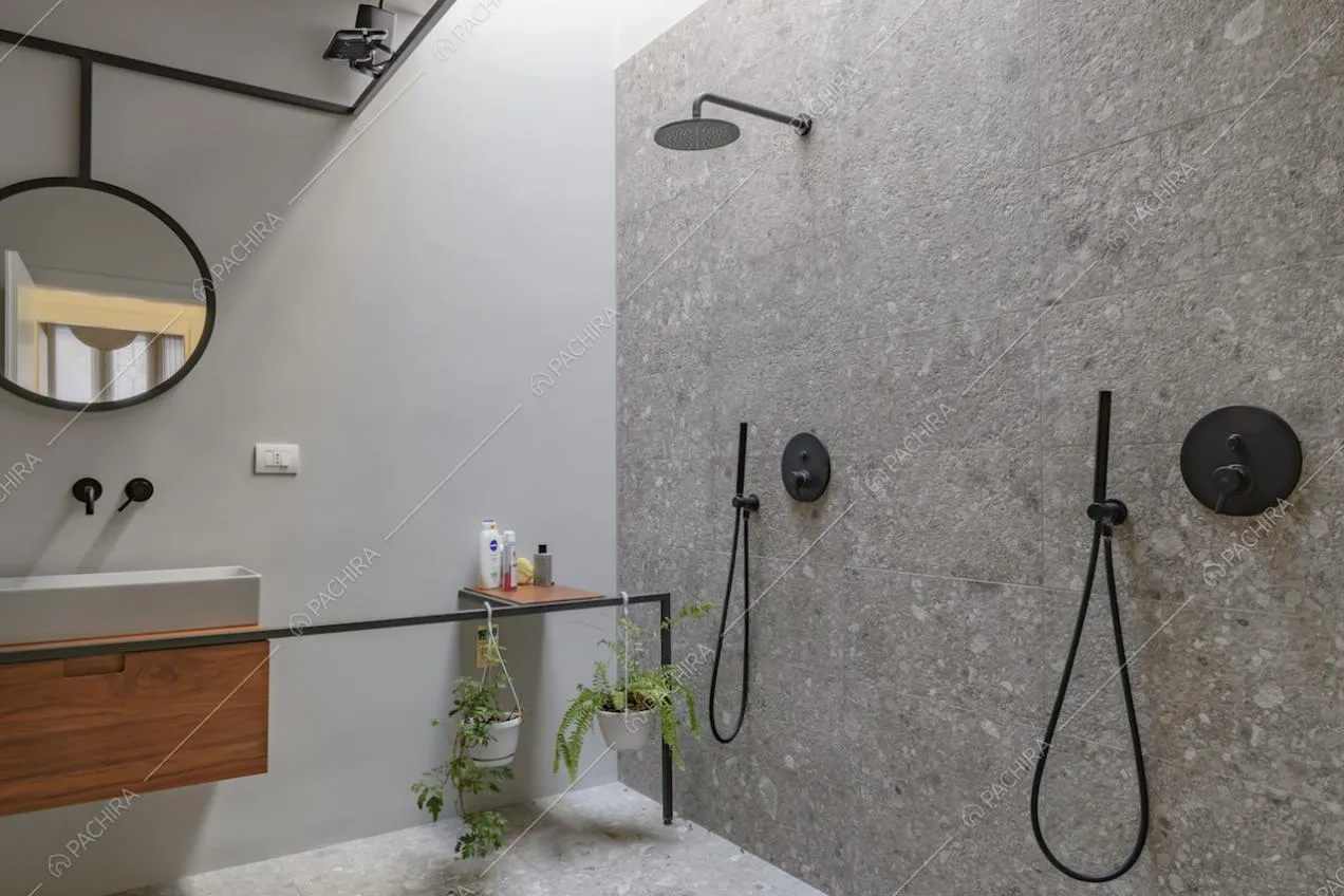 Ampio box doccia con parete in pietra in bagno minimal dalle pareti bianche