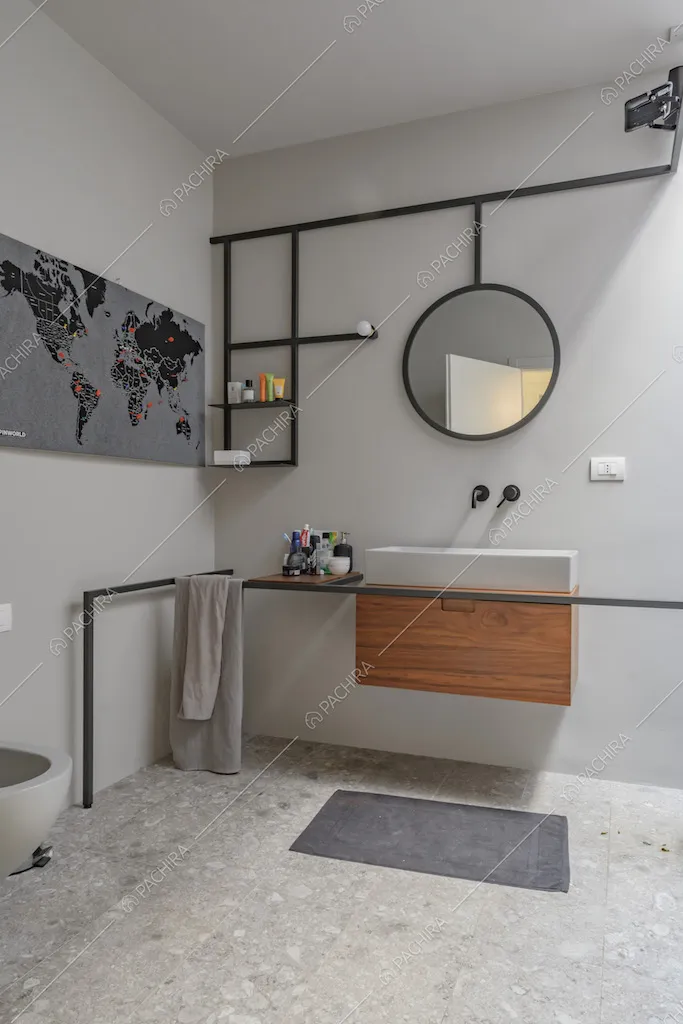 Bagno dalle pareti bianche con pavimento in pietra e mobile del lavabo sospeso