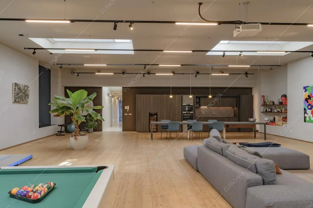 Sala con biliardo, divano angolare grigio e cucina a vista
