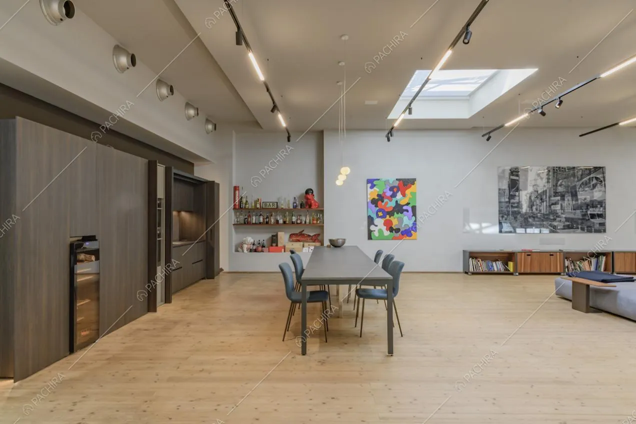 Cucina a vista, illuminata da lucernari, con pavimento in parquet e tavolo da pranzo