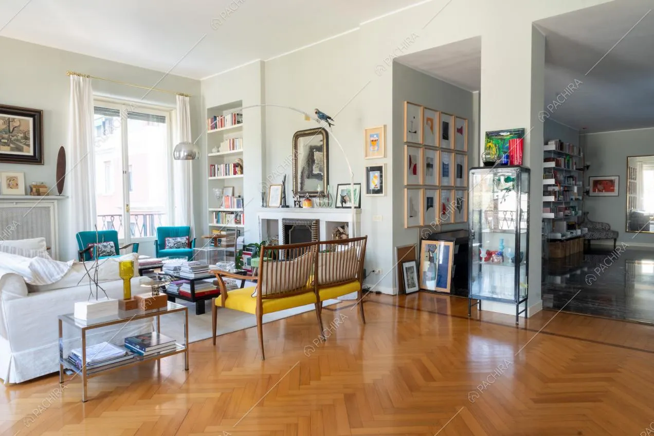 Salotto con divano bianco, porte-finestre che illuminano l'ambiente e parquet a spina di pesce
