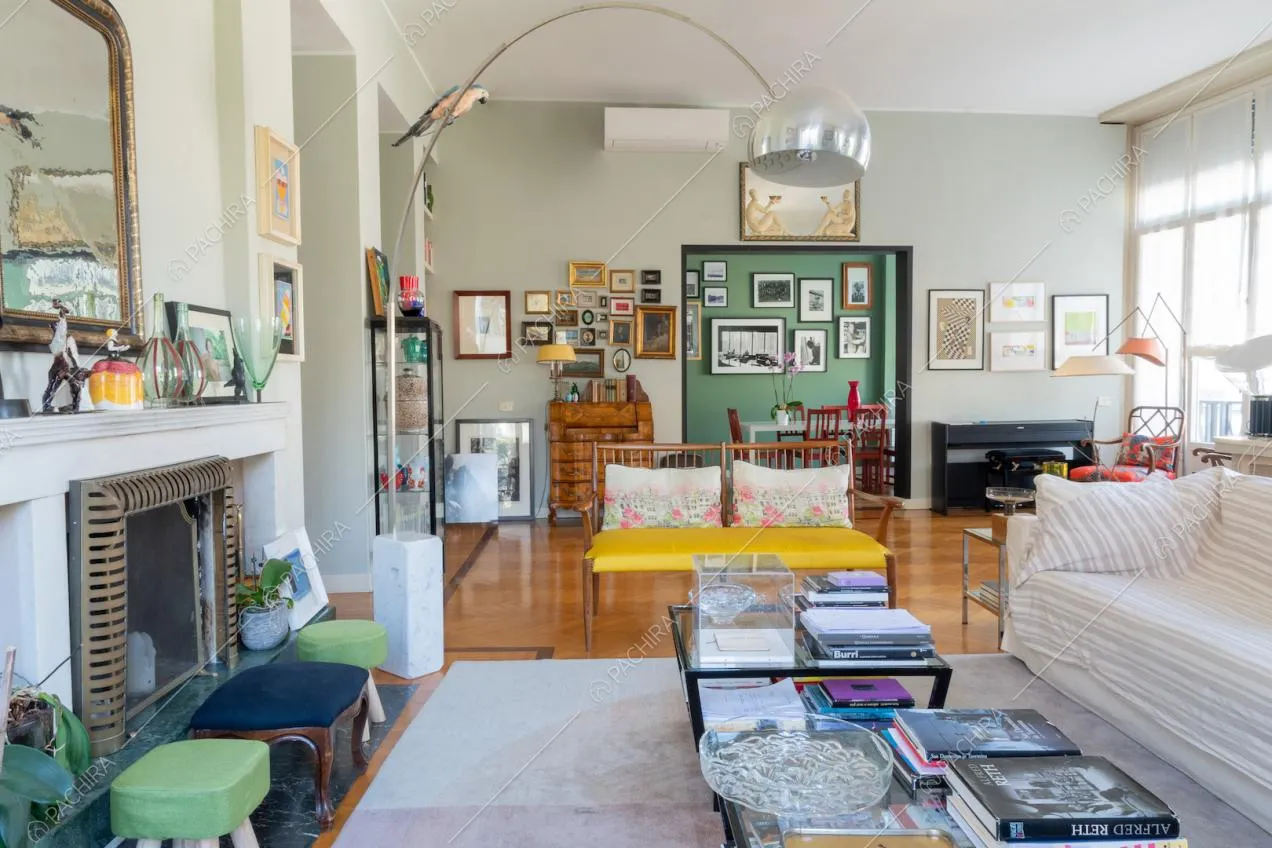Salotto con camino, divani, lampada di design e vista sulla sala da pranzo