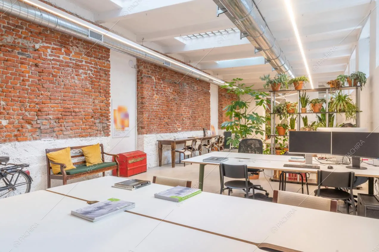 Alcune delle numerose postazioni da lavoro da lavoro della location, sullo sfondo una parete divisoria in...piante!