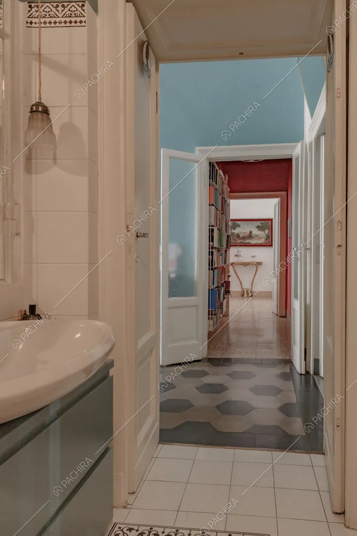 Bagno con pavimento in piastrelle bianche, mobile verde e vista sull'atrio con pavimento in marmo