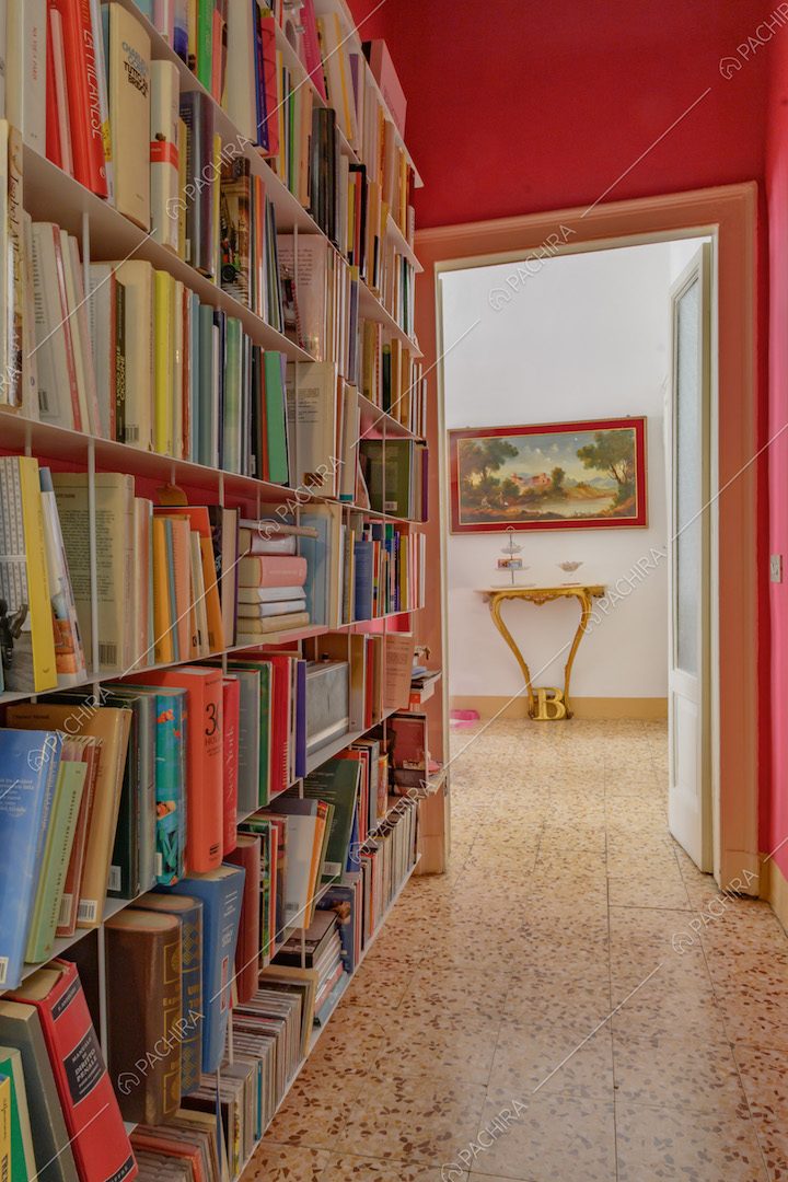 Corridoio con pavimento in marmo, pareti fucsia e libreria