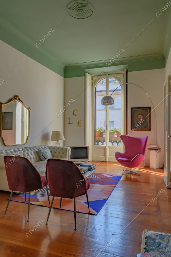 Salotto con pavimento in parquet, soffitto verde con boiserie e porta-finestra bianca