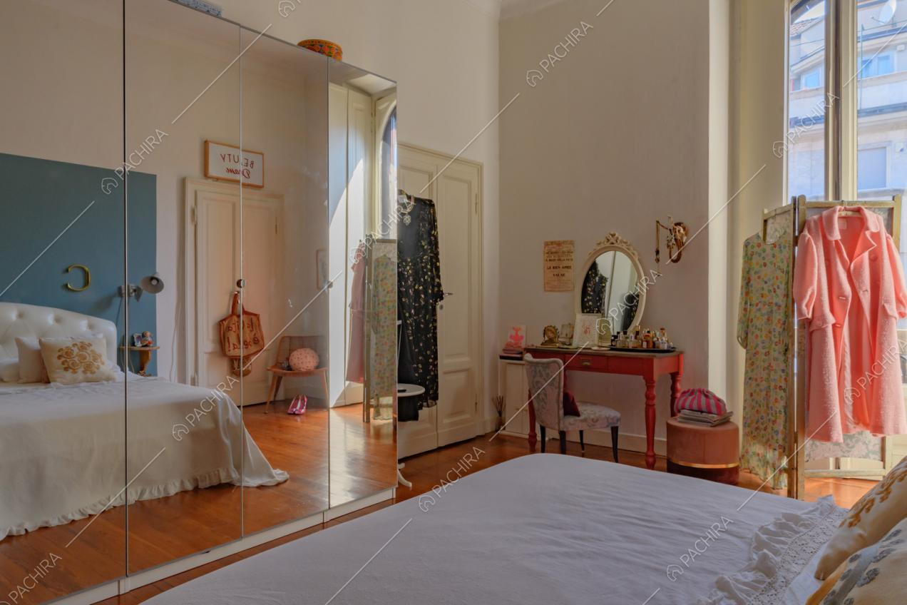 Camera da letto matrimoniale dalle pareti bianche con armadi a specchio e pavimento in parquet