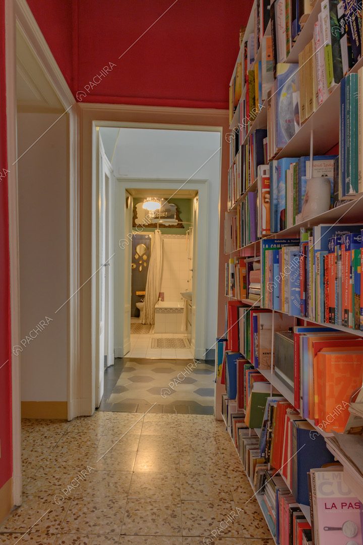 Nel corridoio piastrelle in marmo, libreria, pareti fucsia e vista sul bagno
