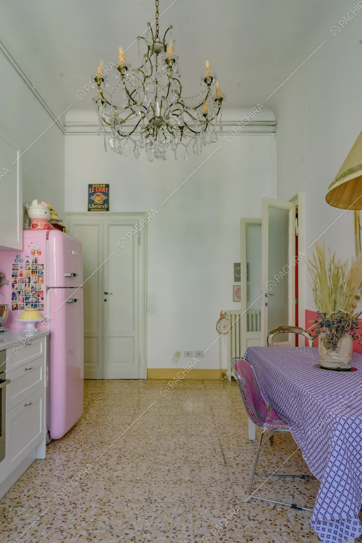 Cucina dalle pareti bianche con boiserie, lampadario e tavolo da pranzo