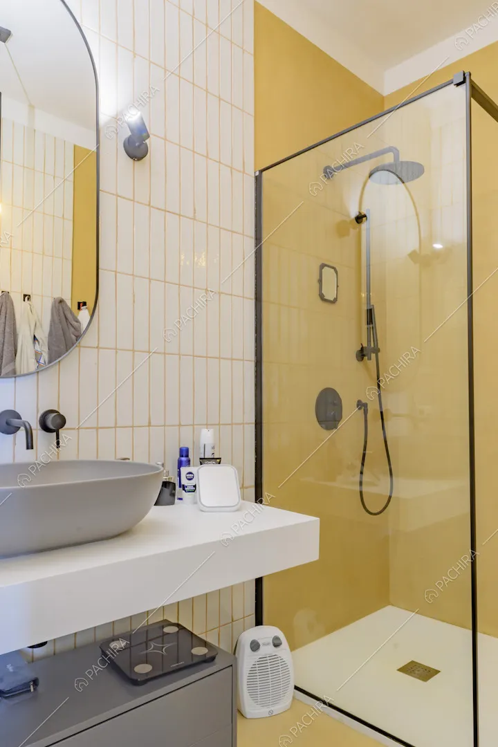Bagno con piastrelle bianche rettangolari e doccia con pareti gialle