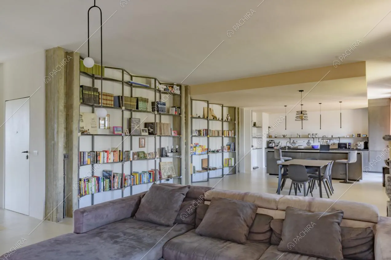 Divano marrone nella zona living con libreria di design e vista sulla cucina a isola